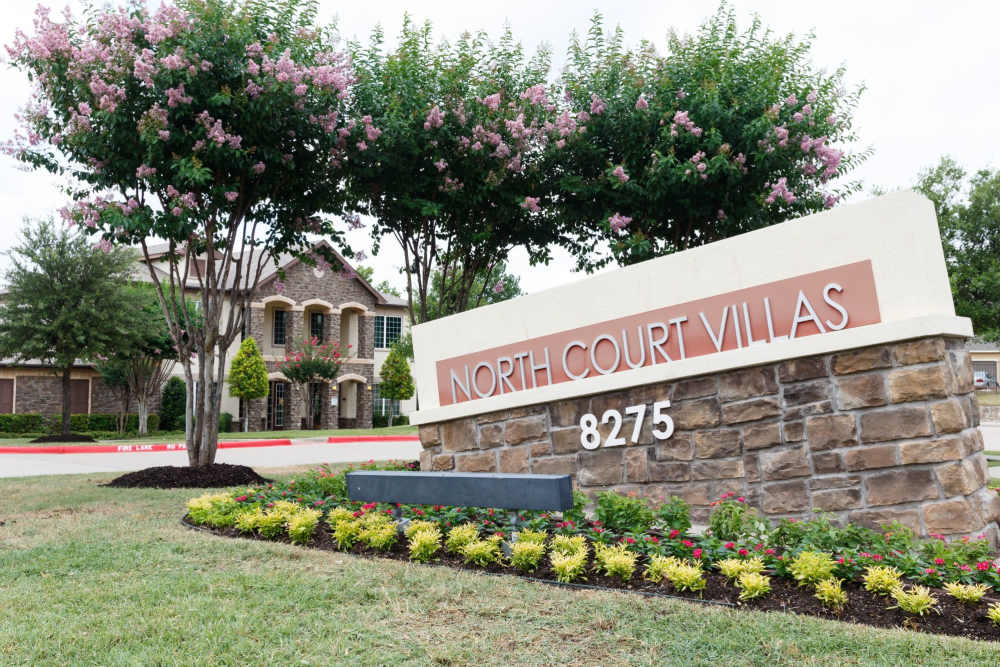 Front entrance sign of community grass and walking paths at North Court Villas in Frisco, Texas